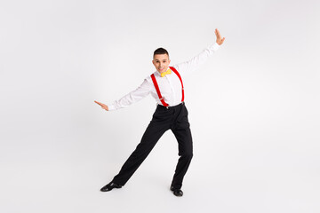 Young male dancer in vibrant suspenders striking a pose against a white background, embodying the...