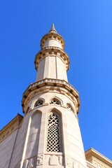 A close-up view of a mosque's minaret against a clear blue sky.