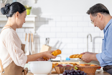 A woman prepares fresh vegetables in a cozy kitchen, while a man assists in the background. The scene emphasizes a warm and healthy lifestyle with a focus on fresh produce and home cooking.