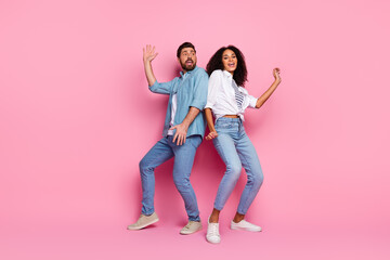 Fototapeta premium Young cheerful couple striking playful poses against a vibrant pink background