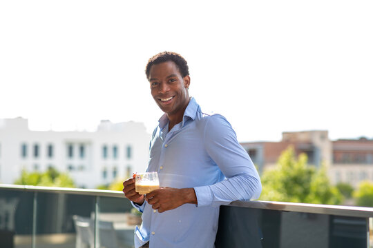 Smiling man holding coffee cup on rooftop terrace - Powered by Adobe