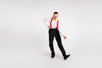Dynamic young man dancing energetically in vintage style outfit with red suspenders and yellow bow...
