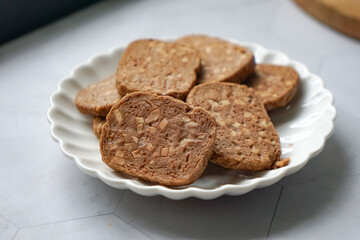A close-up view of delicious chocolate almond cookies neatly arranged on a white plate.  A popular cookies in Malaysia during Eid Mubarak (Hari Raya)