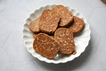 A close-up view of delicious chocolate almond cookies neatly arranged on a white plate.  A popular cookies in Malaysia during Eid Mubarak (Hari Raya)