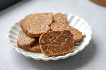 A close-up view of delicious chocolate almond cookies neatly arranged on a white plate.  A popular cookies in Malaysia during Eid Mubarak (Hari Raya)