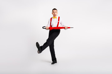 Energetic young man in fashionable retro attire dancing with an umbrella, expressing joy and...