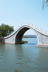 traditional chinese bridge with a large arch on a calm river