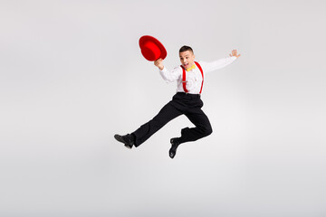 Energetic young man in stylish attire jumping joyfully against a white background, capturing the essence of dance and celebration