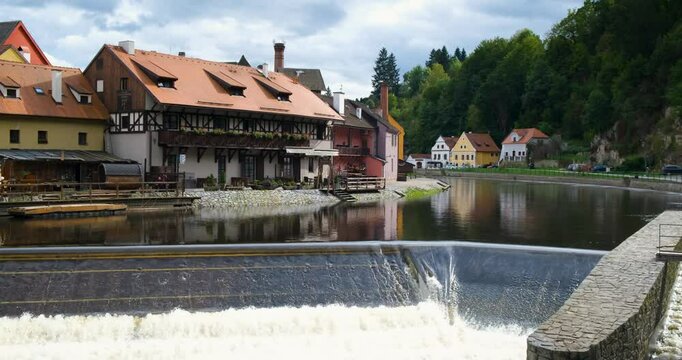 Cinematic composition of an old historical fairy tale town with European architecture colour buildings a big calm river and mountain in background and small river dam threshold and foamy clean water