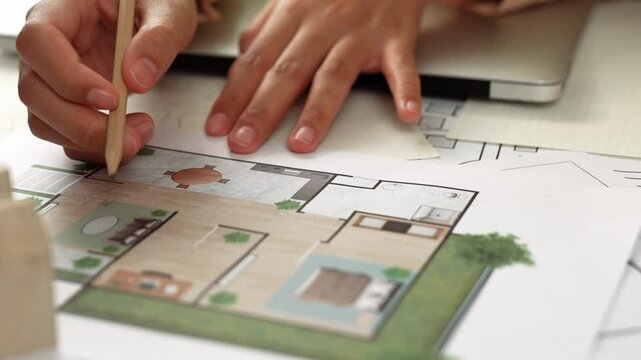 Professional engineer team discussion about house design on meeting table with architectural equipment and building blueprint scatter around at modern office. Focus on hand. Closeup. Delineation.