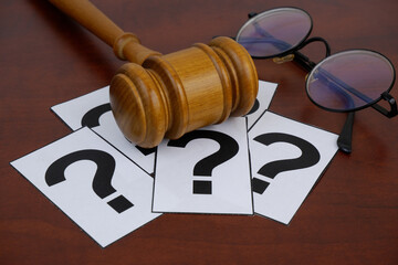 Judge gavel, question marks cards and round eyeglasses. Legal questions concept.	