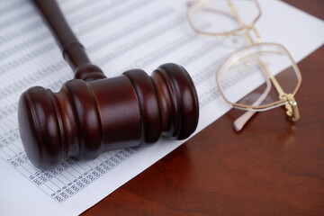 Close up of judge gavel, eyeglasses and financial papers on table. Audit and financial fraud...
