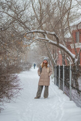 Young woman walks in the park in nature in winter, enjoing winter day at snowy park. Winter concept. High quality photo.