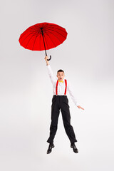 Young man dancing joyfully with red umbrella on white background