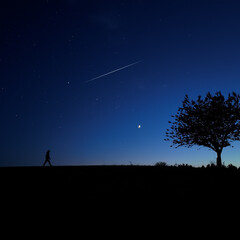 Silhouette of a man and countryside under the stars and Moonlight.