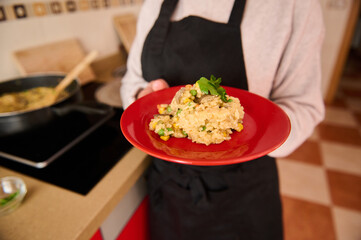Person holding a plate with delicious vegetable paella garnished with fresh herbs