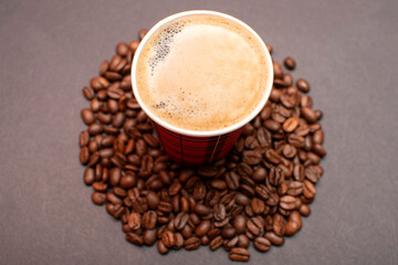 Paper cup with coffee on roasted coffee beans