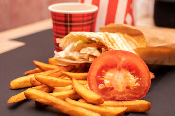  French fries, shawarma, slice of a tomato and paper coffee cup