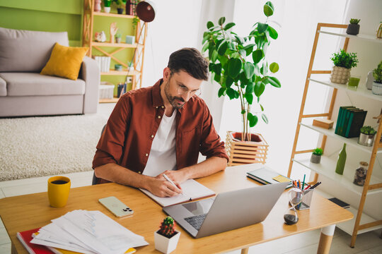 Young man working at home surrounded by plants in a stylish and cozy living space - Powered by Adobe