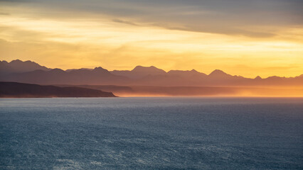 Majestic seascape with golden light in the morning during sunrise with mountains and ocean along the Garden route, Plettenberg Bay, Western Cape province, South Africa, Africa