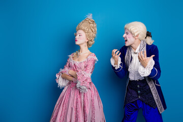 Elegant couple in historical attire with blue backdrop showcasing classic fashion and aristocratic...