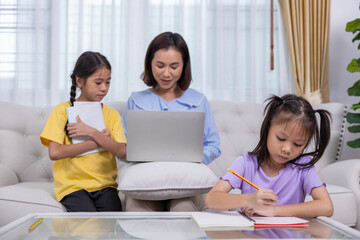 Happy family, mother and daughter are having fun teaching their two daughters homework