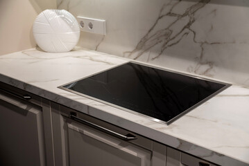 Black induction cooktop integrated into a marble kitchen countertop