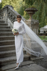 An Elegant Bride Adorned in a Stunning White Lace Dress on Beautiful Garden Stairs