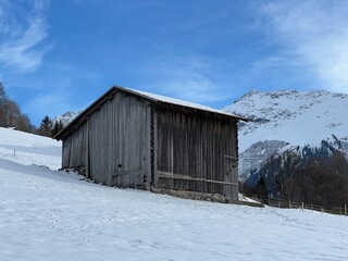 Old traditional swiss rural architecture and alpine livestock farms in the winter ambience of the alpine Swiss tourist resort Klosters - Canton of Grisons, Switzerland (Kanton Graub&uuml;nden, Schweiz)
