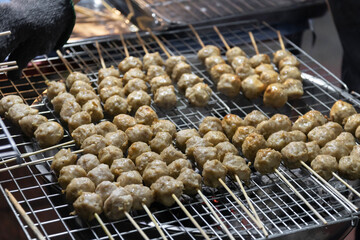 Grilled skewers of meatballs on a barbecue grill.