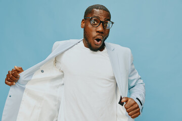 Stylish man in glasses expressing surprise in a light suit against a blue background, showcasing...