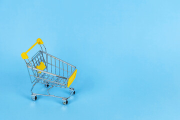 An empty shopping cart on a blue background. Concept of shopping, sales, online trading, purchases, shops, retail, market. Copyspace for text