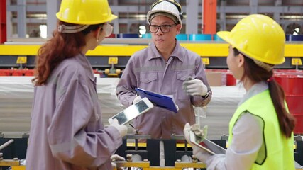 Group of engineers in safety gear reviewing machinery operations in a manufacturing facility, focused on production efficiency and teamwork.