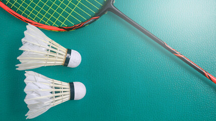 White badminton shuttlecocks and badminton rackets on green floor indoor badminton court. Concept for badminton competition and its lovers.