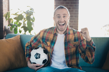 Excited young man with beard enjoying leisure time at home in stylish shirt