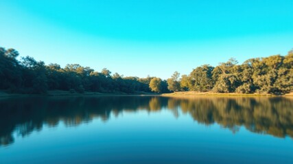 Serene Lakeside Vista Tranquil Water Reflecting Lush Green Foliage Under a Clear Blue Sky