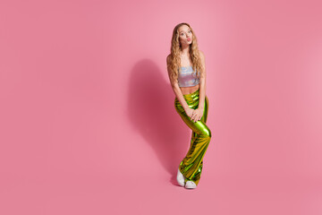 Stylish young woman in trendy outfit posing against vibrant pink background, expressing playful...