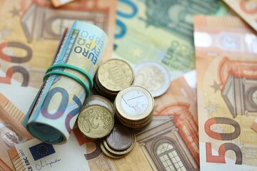 Roll of euro currency money bills and many euro cents on banknotes of european union