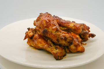 White plate with small brown basted and cooked chickenwings.