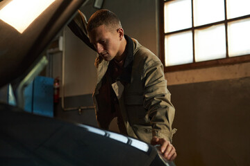 Professional mechanic examining the car in garage