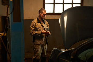 Fototapeta premium Mechanic opening the bonnet and repairing broken car in car service