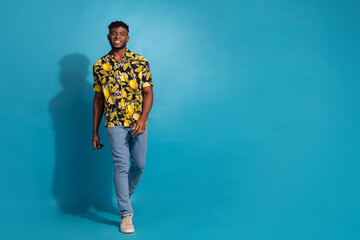 Stylish young man enjoying summer day in trendy printed shirt against vibrant blue background