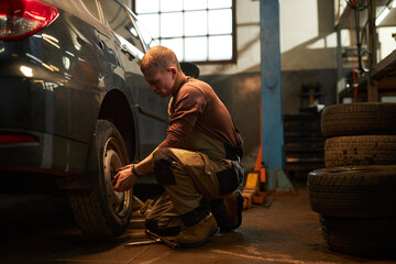 Fototapeta premium Mechanic examining the wheels of car in service