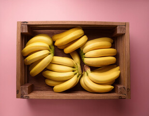 Fresh yellow bananas are neatly arranged in a wooden crate against a pink background.