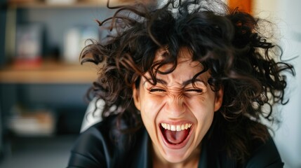 Close-up portrait of a joyful woman with curly hair laughing.