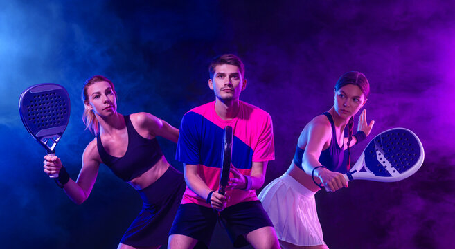 Three Padel tennis players with racket on open tournament. Girl, woman and man athletes with paddle racket on court. Sport concept. Padel tour event. - Powered by Adobe