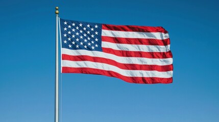Fototapeta premium American Flag Waving Against Clear Blue Sky in Bright Sunlight