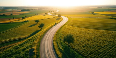 Fototapeta premium Serene Sunset Over Rolling Farmland and Winding Road