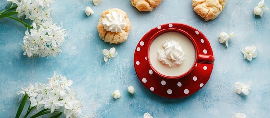 Delicious profiteroles on a blue background with a red polka dot coffee cup filled with milk and cream topped with fresh white hyacinths