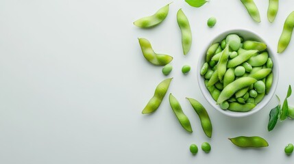 Fresh green edamame soybeans and pods arranged artistically with a bowl on white background showcasing healthy snacking options.